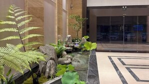 A modern indoor garden with a water feature, large green leaves, and a marble floor. - Boying Business Hotel (Jiangmen)