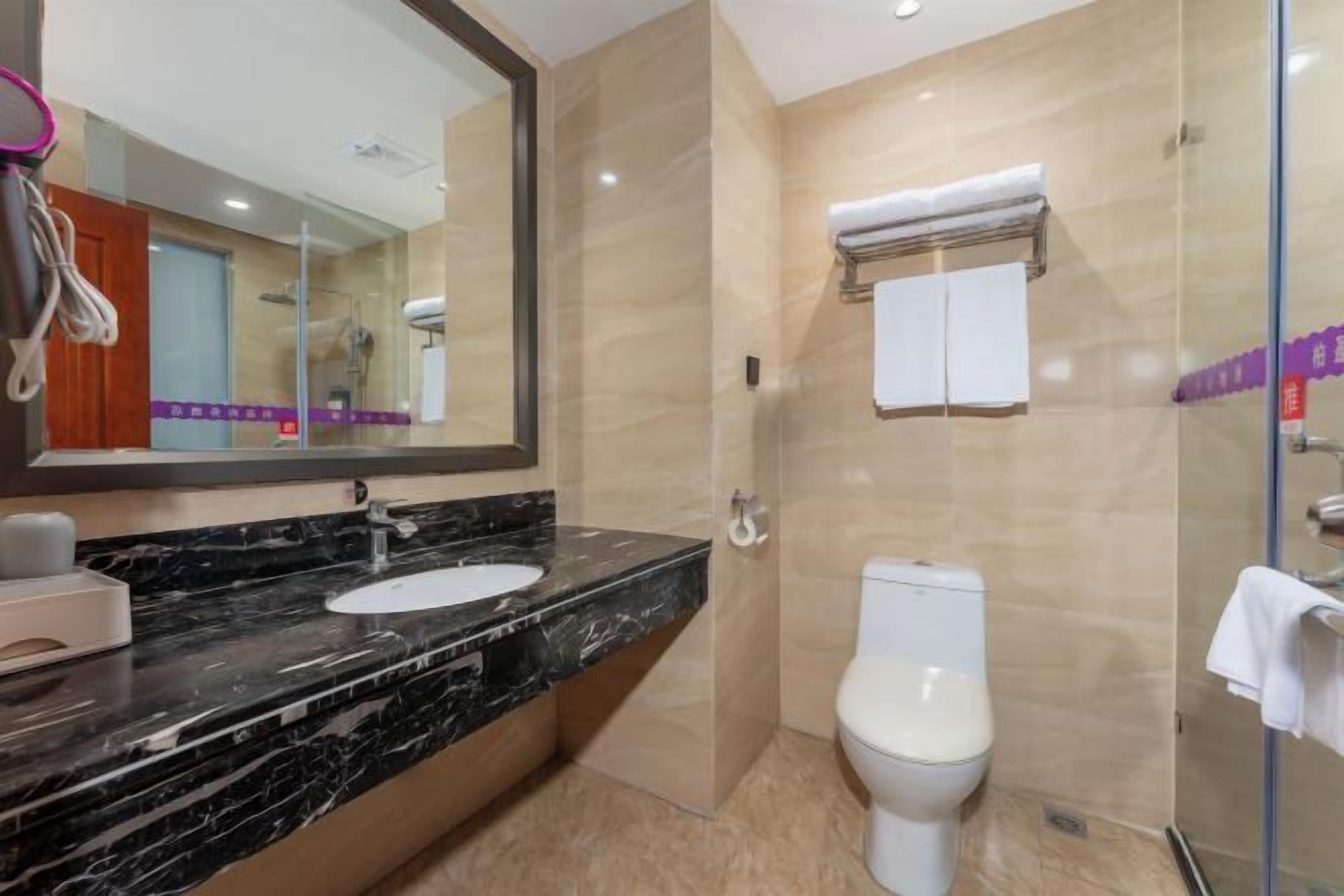 A modern bathroom with a marble sink, a toilet, and a glass shower enclosure.