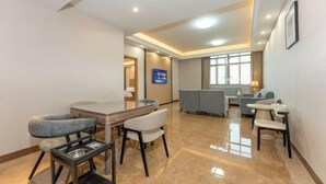 A modern hotel room with a dining area, a TV, and a seating area with a view. - Boying Business Hotel (Jiangmen)