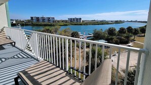 Een balkon met uitzicht op een rivier, boten en gebouwen aan de overkant van het water.