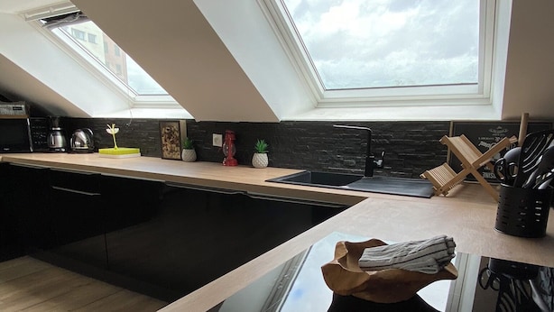 Eine moderne Küche mit Oberlicht, schwarzem Arbeitsplatz und Holzboden.