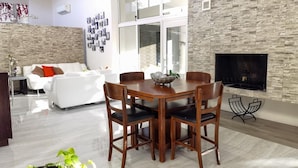 A modern living room with a dining table, white sofa, and a fireplace.