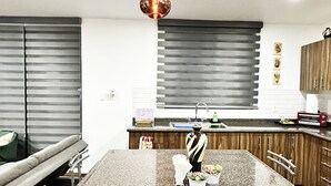 Une cuisine moderne dotée d’un plan de travail en granit, de meubles en bois et d’un luminaire suspendu.