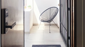 Une entrée moderne avec une pancarte « Bienvenue », une chaise noire et un portail en métal.