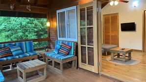 Une terrasse en bois avec un canapé et des fauteuils, une table et un téléviseur.