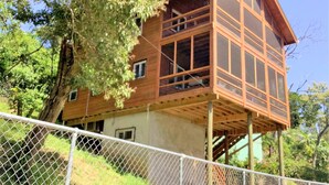 Une cabane en bois dotée d’un balcon, entourée d’arbres.