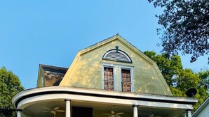A two-story house with a porch, a stone retaining wall, and a satellite dish. - The Historic Myrna Loy House, Downtown Hot Springs (Hot Springs)