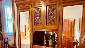 A wooden armoire with intricate carvings, a mirror, and a bed in the background. - The Historic Myrna Loy House, Downtown Hot Springs (Hot Springs)