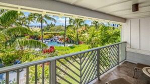 Ein Balkon mit Blick auf einen angelegten Garten, einen Swimmingpool und eine ferne Meerblick.
