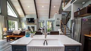 A modern kitchen with a large island, built-in appliances, and a dining area with a view. - Cozy Lakefront! Lac La Nonne, Alberta (Barrhead County No.11)