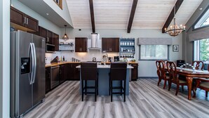 A modern kitchen with a central island, stainless steel appliances, and wooden flooring. - Cozy Lakefront! Lac La Nonne, Alberta (Barrhead County No.11)
