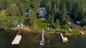 A large house surrounded by dense forest, docked boats, and a clear view of the water. - Cozy Lakefront! Lac La Nonne, Alberta (Barrhead County No.11)