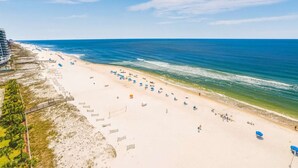 Une plage offrant une vue dégagée sur l’océan, une rive sablonneuse et un bâtiment situé à côté de la plage.