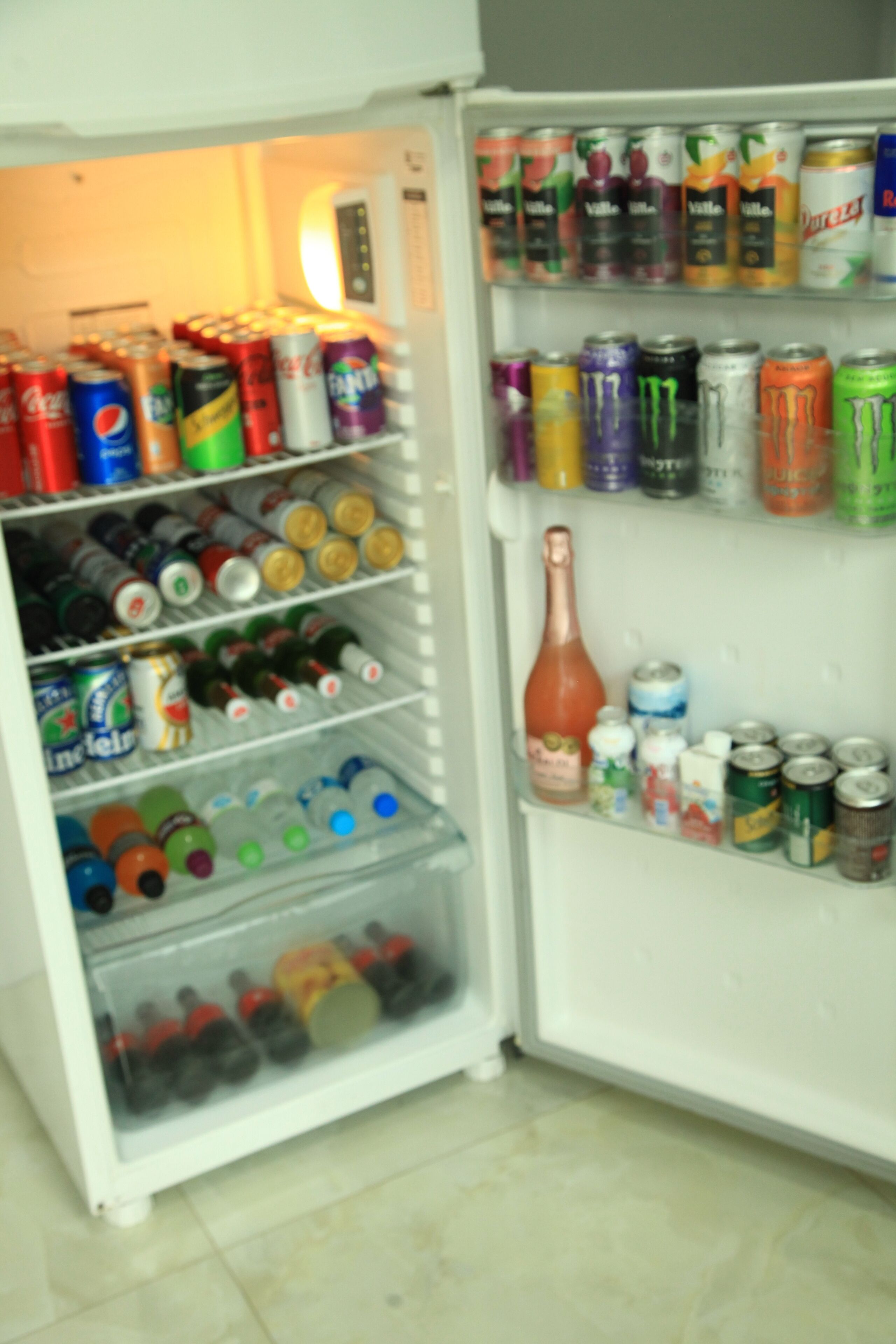 A refrigerator stocked with various beverages including sodas, energy drinks, and bottled water.