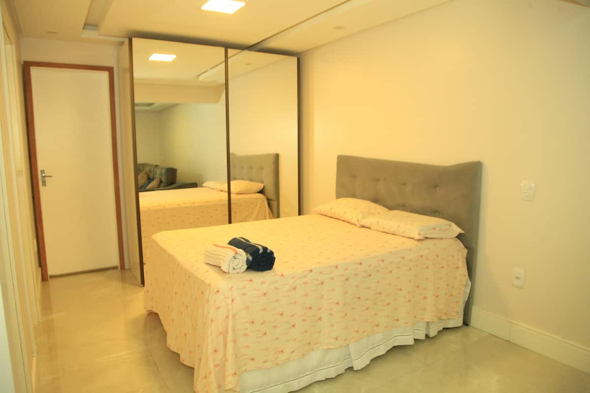 A bedroom with a bed, a mirror, and a door.