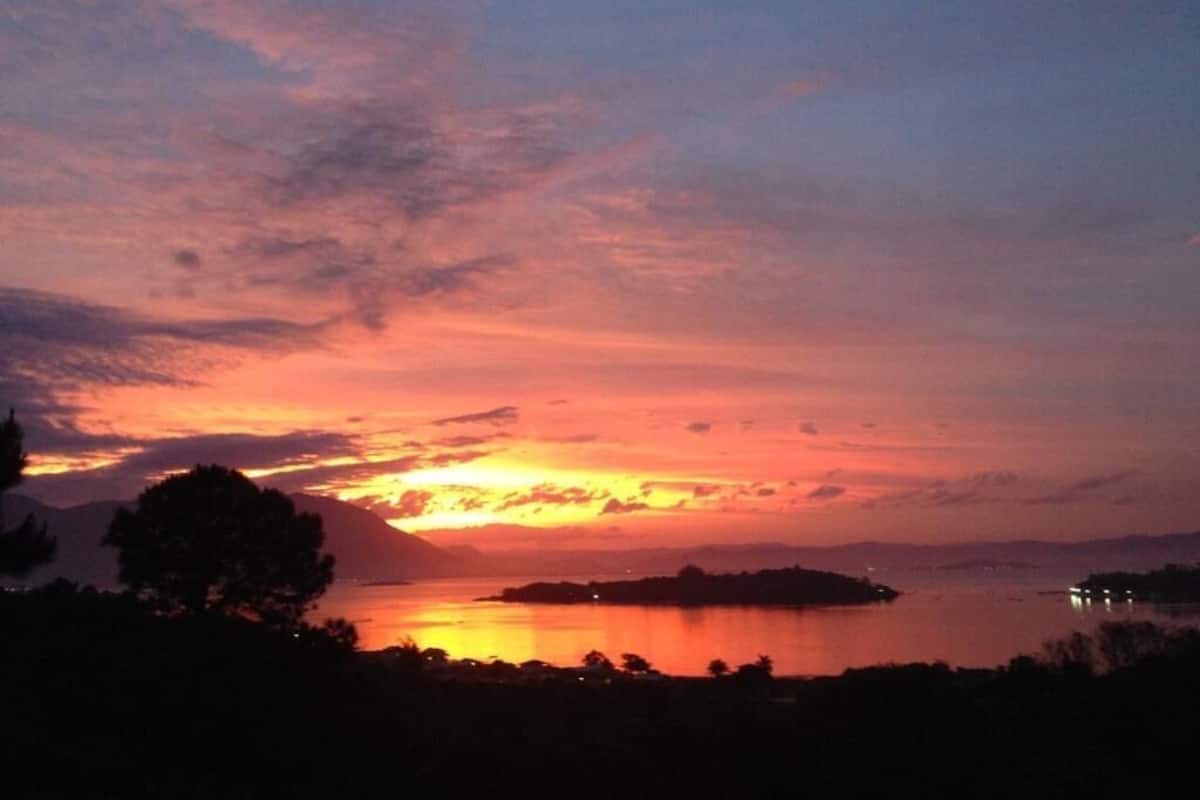 A sunset over a calm body of water with a distant island.