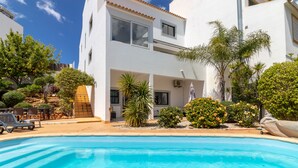 A two-story white building with a swimming pool, outdoor seating, and various plants. - Sunny family villa with pool, 10 mins from the beach and centre! (Ferragudo)