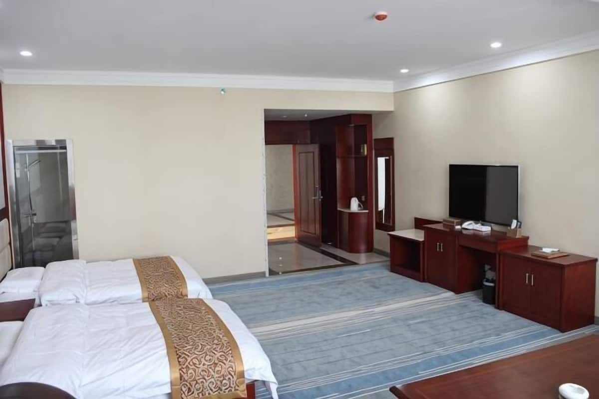 Ein Hotelzimmer mit einem großen Bett, einem Fernseher, einem Schreibtisch und einem durch eine offene Tür einsehbaren Badezimmer.