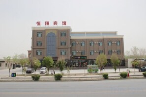 A multi-story building with a prominent entrance and signage. - Hengxiang Hotel (Aksay)