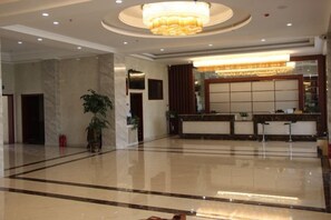 A hotel lobby with a reception desk, a large chandelier, and a polished floor. - Hengxiang Hotel (Aksay)