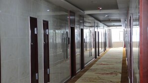 A long hallway with a patterned carpet, glass doors, and a tiled wall. - Hengxiang Hotel (Aksay)