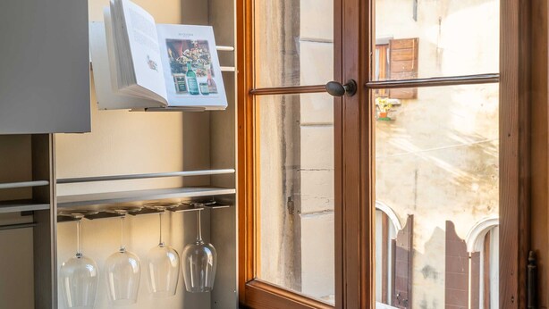Une cuisine avec un porte-bouteilles contenant trois verres à vin et un livre posé sur une étagère.