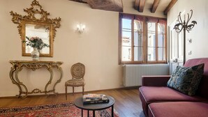 Une pièce avec un plafond en bois, un grand miroir, un canapé, une chaise et une petite table sur laquelle sont posés des livres.