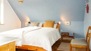 Un dormitorio con cama, mesitas de noche, una silla y una lámpara.