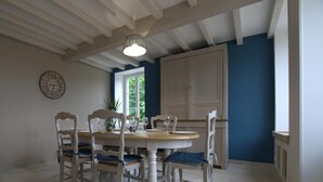 Zona pranzo con un tavolo rotondo e sei sedie, una ventola a soffitto e una finestra vista verde.