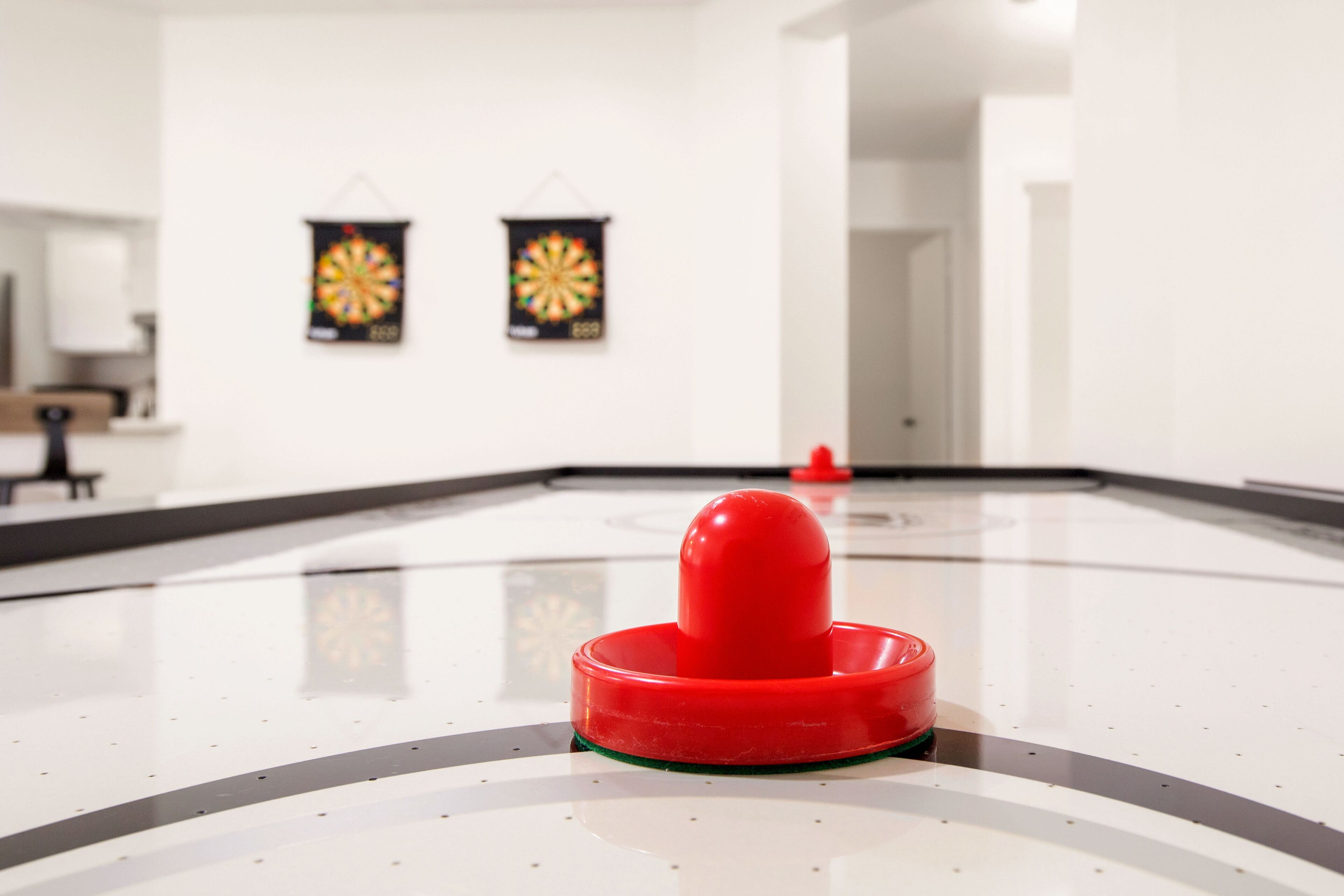 A dartboard and a dart on a polished floor in a room with white walls and a door in the background.