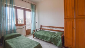 Ein Schlafzimmer mit zwei Einzelbetten, einem Holzschrank und einem Fenster mit Vorhängen.