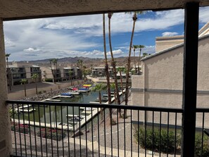Vista de un puerto deportivo con barcos amarrados, rodeado de palmeras y edificios.