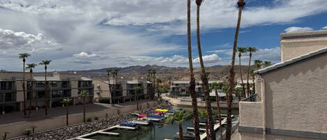 A resort with a marina, palm trees, and a mountainous backdrop.