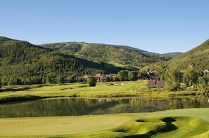 A golf course with a lake, surrounded by forested hills and residential buildings. - Charlie's Slopeside: Ski-In/Out, Sleeps 10, 2 Master Suites, Pool + Hot Tub, Alpine Club (Avon)