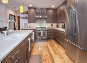 A modern kitchen with stainless steel appliances, wooden cabinets, and a marble countertop.