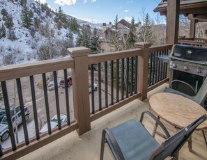 A balcony with a view of a snowy mountain, a barbecue grill, and a table with chairs. - Charlie Rentz: Ski-In/Out, Sleeps 10, 2 Master Suites, Pool + Hot Tub, Alpine Club (Edwards)