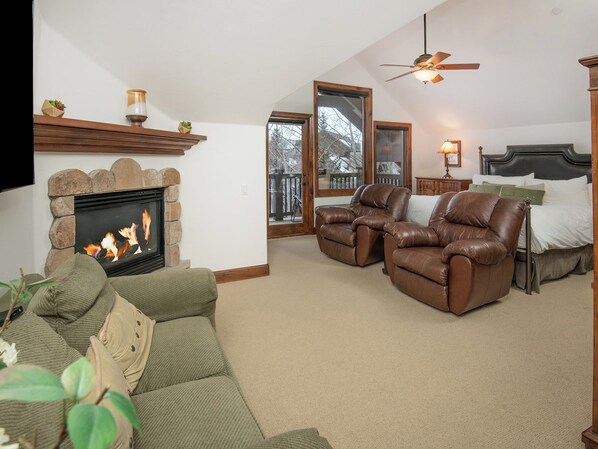 A living room with a fireplace, leather recliners, a sofa, and a bed.