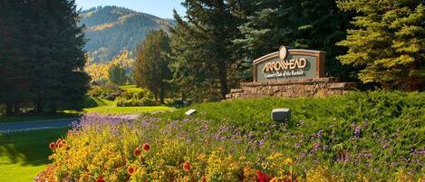 A sign for Arrowhead Country Club of the Rockies with a landscaped garden in the foreground.