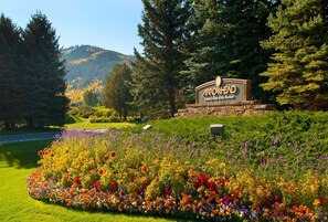 A sign for Arrowhead Country Club of the Rockies with a landscaped garden in the foreground.
