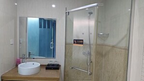 Un baño moderno con un lavabo redondo, un espejo y una ducha con mampara de vidrio.