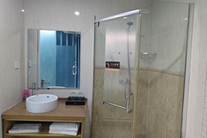 Un baño moderno con un lavabo redondo, un espejo y una ducha con mampara de vidrio.
