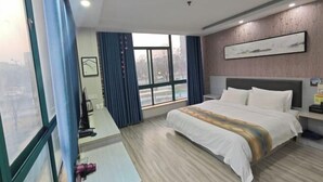 Una habitación de hotel moderna con una cama grande, un escritorio y una ventana con cortinas.