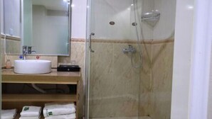 Baño con lavamanos, espejo y ducha.