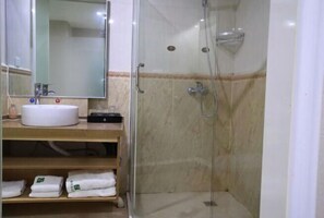 Une salle de bain avec un lavabo, un miroir et une douche.