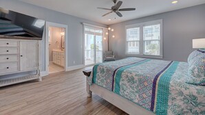 A bedroom with a bed, a ceiling fan, and a view of the outside.