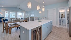 A spacious kitchen with a large island, pendant lights, and a view to the dining area.