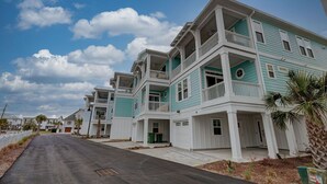 A row of two-story houses with balconies, a clear sky, and a street in front.
