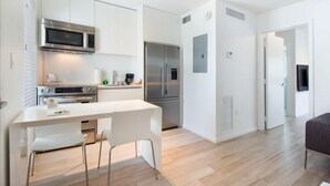 Una cocina moderna con armarios blancos, electrodomésticos de acero inoxidable y una isla central con sillas.