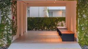 Un espace de détente intérieur avec des bancs et un petit muret recouvert de verdure.