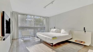 Une chambre moderne avec un grand lit, une chaise et un téléviseur fixé au mur.